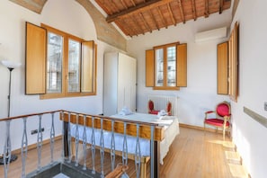 Experience the charm of traditional European architecture in this cozy room featuring a wooden staircase, plush bed, and elegant wooden ceiling.