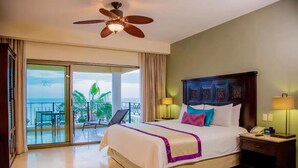 A hotel room with a bed, a nightstand, a ceiling fan, and a balcony with a view of the ocean.