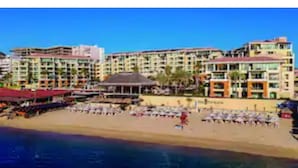 A beachfront hotel with multiple balconies, a pool area, and a beachside bar.