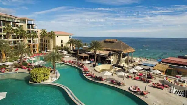 A resort with a large pool, beachside lounge, and ocean views.