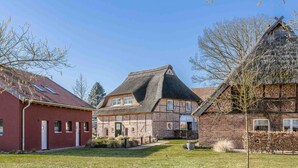 A traditional European village with red brick houses, a thatched-roof building, and a well-maintained lawn. - Manor Bockelkathen – Apartment 7 (Lüdersburg)