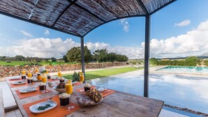 An outdoor dining area with a view of a swimming pool and a stone wall. - Modern villa in Mallorca Pleta with swimming pool (Manacor)