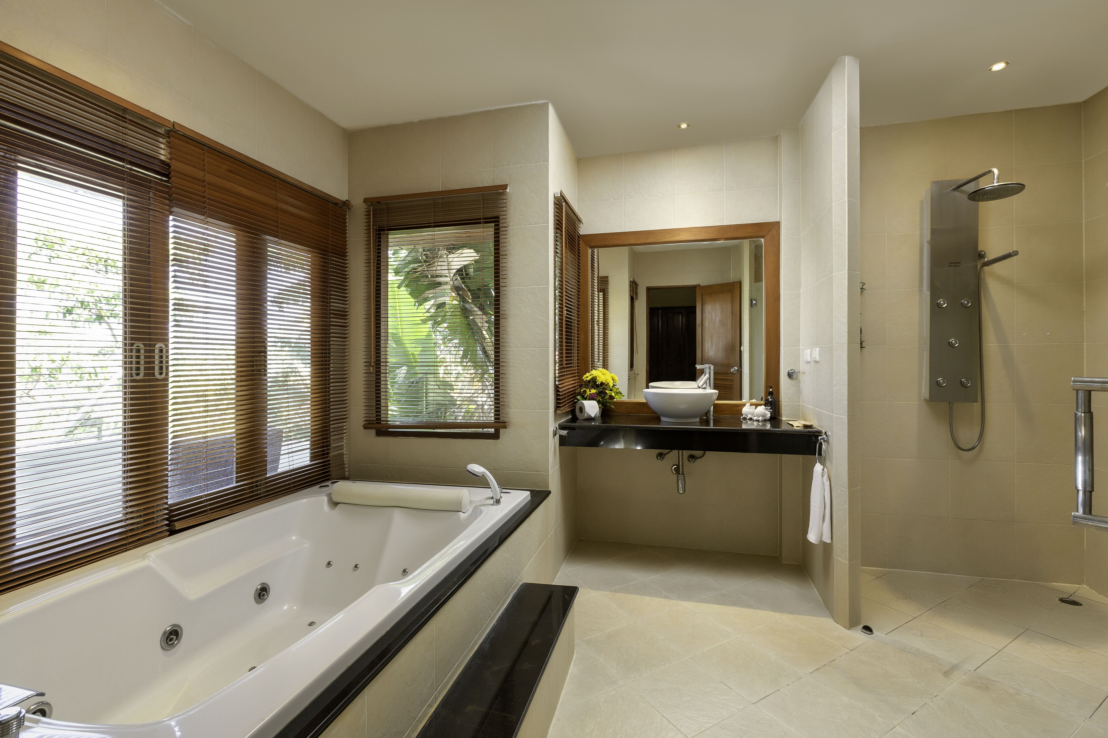 A modern bathroom with a large bathtub, a separate shower area, and a vanity with a sink and mirror.