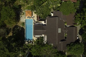 Ein Luftbild eines Hauses mit Schwimmbad, überdachter Terrasse und großem Garten.