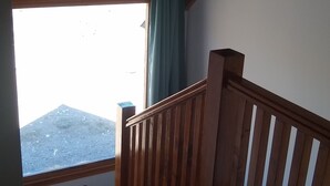 Een kamer met een houten plafond, een raam met uitzicht en een houten leuning.