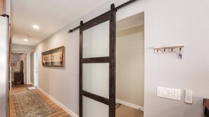 A hallway with a wooden floor, a sliding door, a framed picture on the wall, and a light switch. - Casa Azul (Seal Beach)
