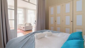 Une chambre à coucher comprenant un lit, une armoire et donnant sur un espace de vie.
