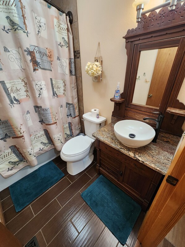 A bathroom with a toilet, sink, and shower curtain with inspirational quotes.