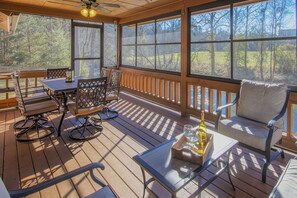 A wooden deck with a table, chairs, and a sofa.