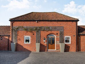 A red brick building with a tiled roof, a wooden door, and a small window.