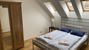 Ein Schlafzimmer mit Bett, Kleiderschrank, Nachttisch, Lampe und Dachfenstern.