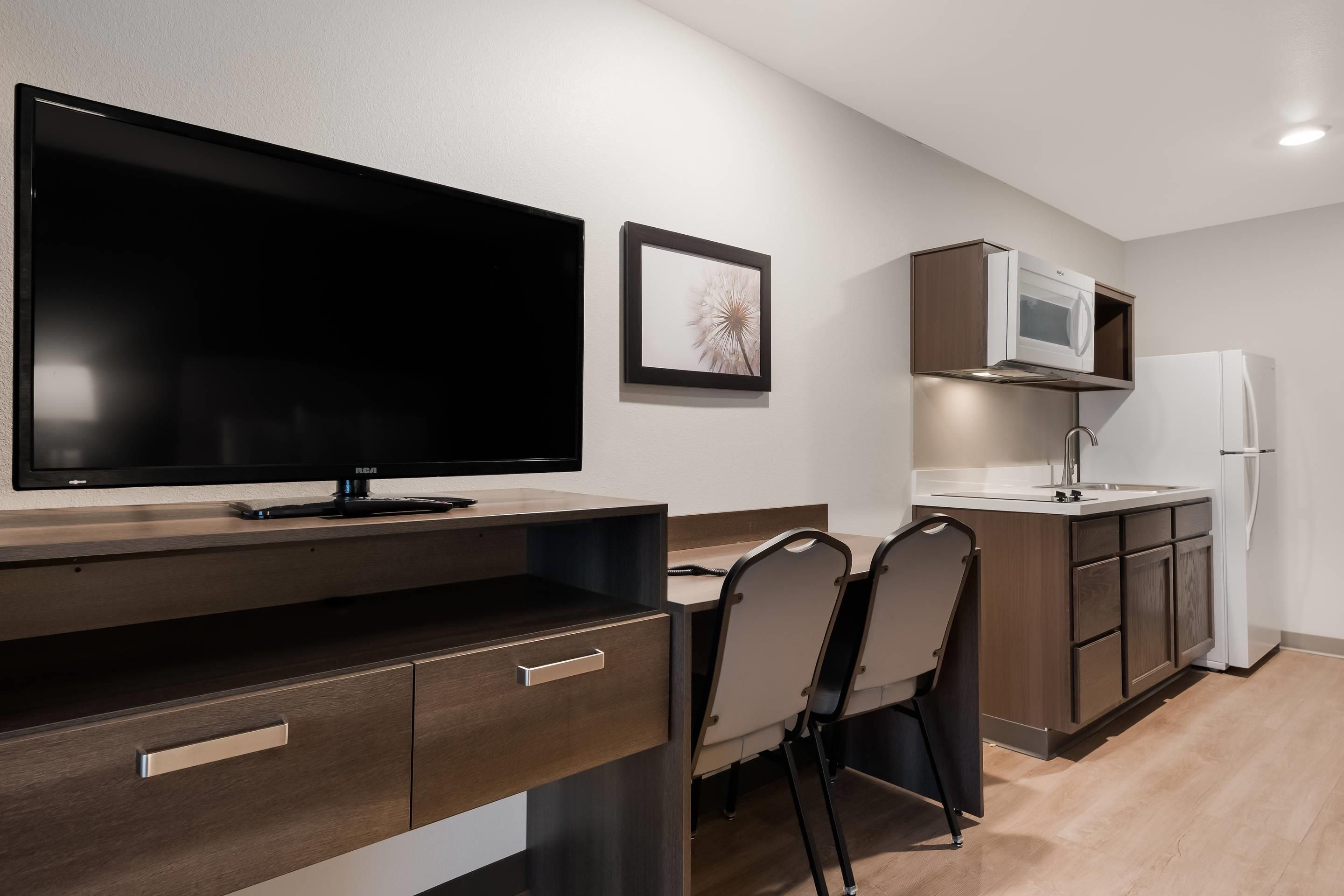 A modern kitchen with a flat-screen TV, a microwave, and a refrigerator.