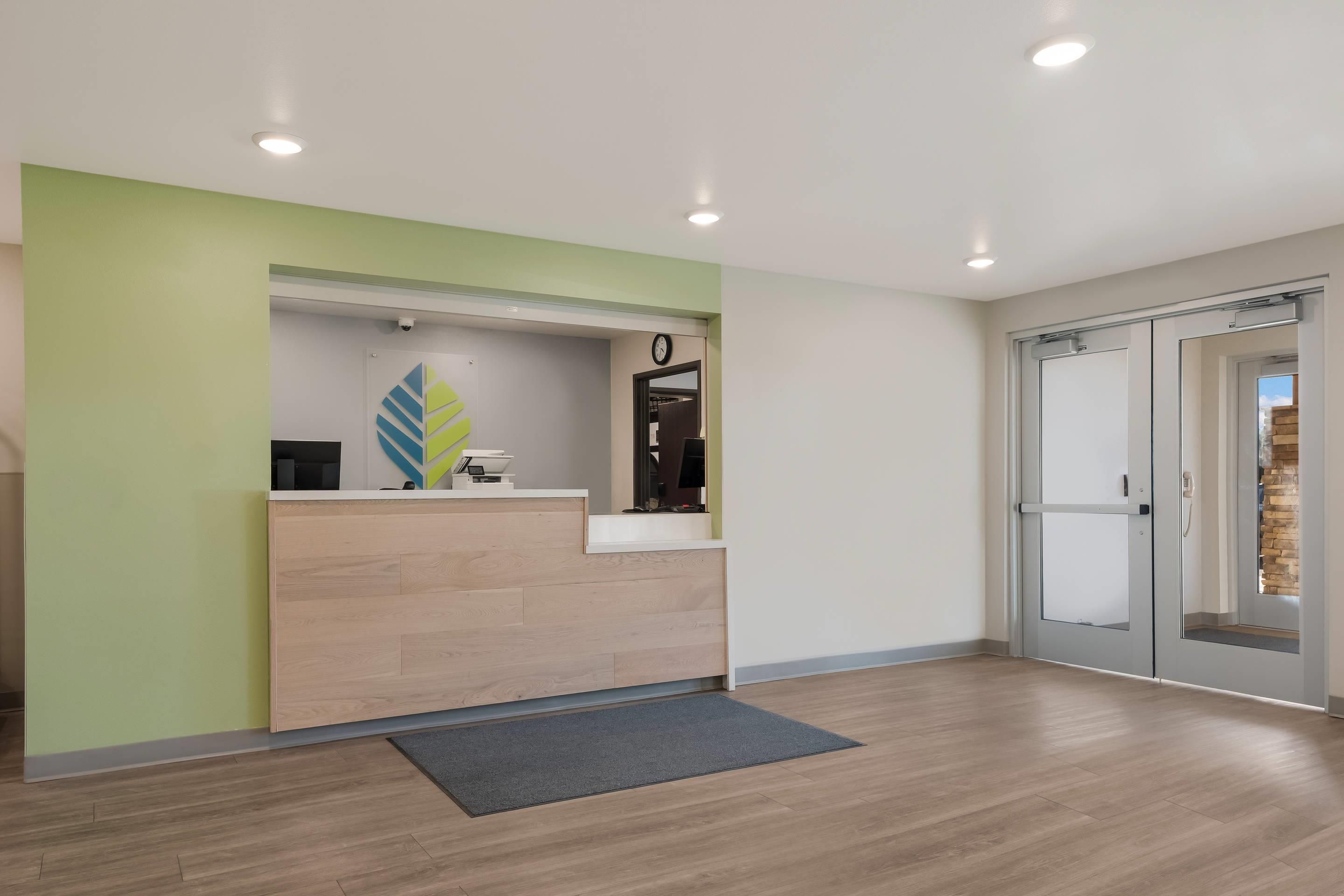 A reception area with a wooden reception desk, a clock, and a glass door leading to another room.