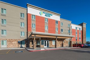 A two-story hotel with a modern facade, a prominent sign for Woodspring Suites, and a parking lot with marked spaces. - WoodSpring Suites Phoenix-Deer Valley (Phoenix)
