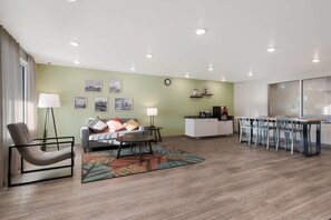A modern living room with a sofa, coffee table, and a dining area with chairs and a table. - WoodSpring Suites Phoenix-Deer Valley (Phoenix)