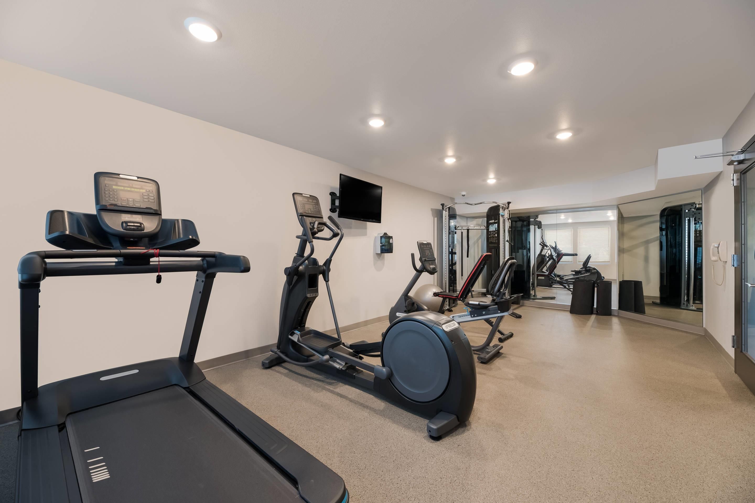 Un gimnasio con cintas de correr, elípticas y equipo de pesas.