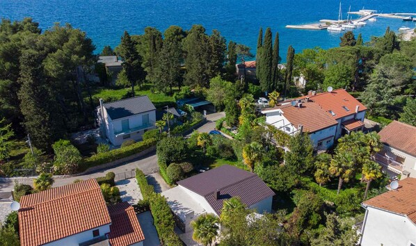 An aerial view of a coastal residential area with houses, a marina, and dense greenery.
