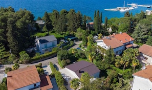 Vue aérienne d’une zone résidentielle côtière, avec des maisons, une marina et une végétation luxuriante.
