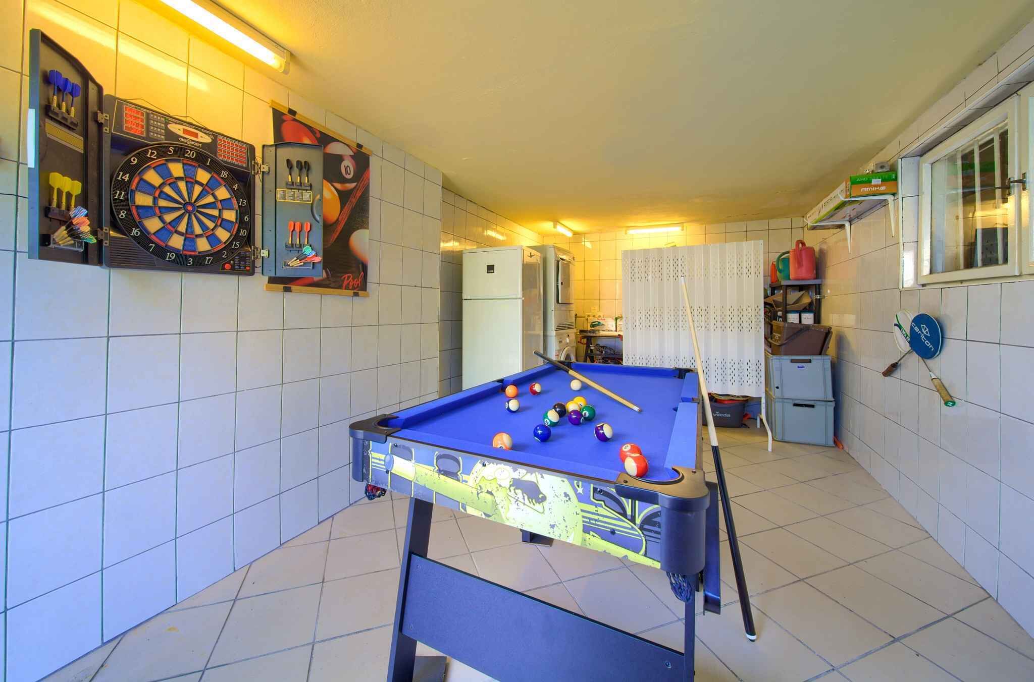 Ein Zimmer mit Billardtisch, Dartscheibe und Kühlschrank.