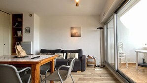 En moderne stue med et træspisebord, grå stole, en grå sofa og et stort vindue med udsigt.