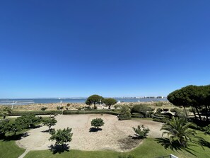 A landscaped garden with a view of the sea, featuring neatly trimmed hedges and a variety of trees.