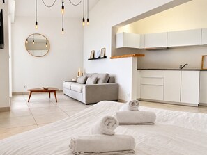 Une chambre moderne avec un grand lit, un canapé, une table à manger et un coin cuisine.