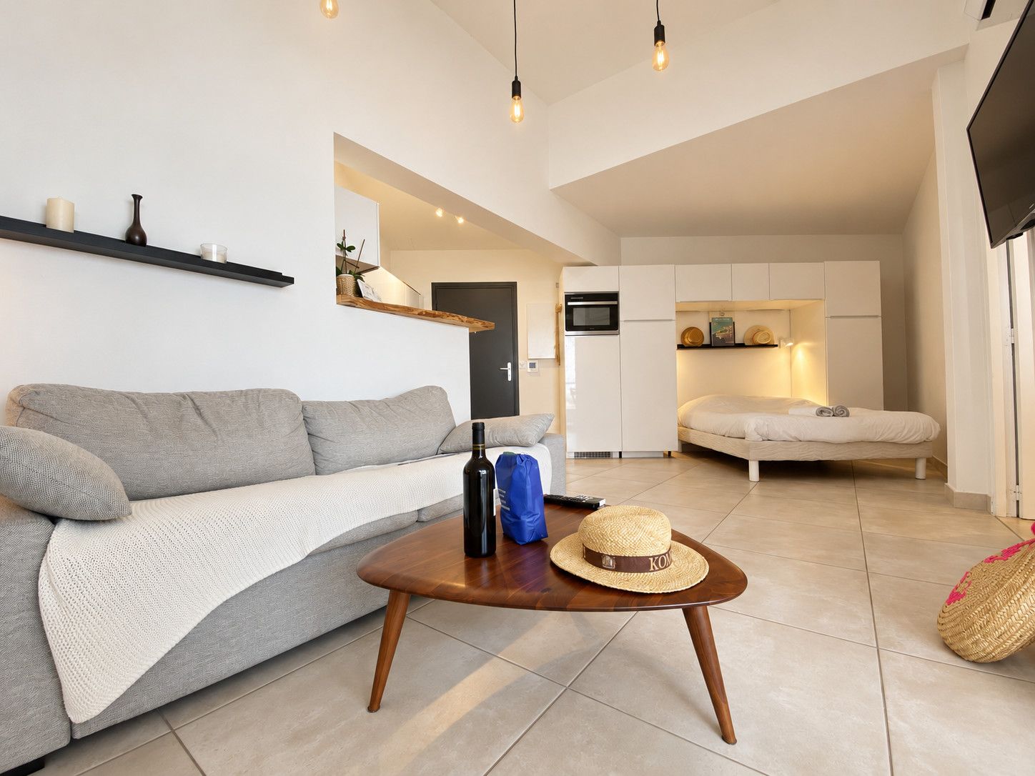 Een moderne woonkamer met een bank, een salontafel en een keukenhoek met een bed.