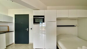 Una habitación pequeña con kitchenette, una cama y una puerta.