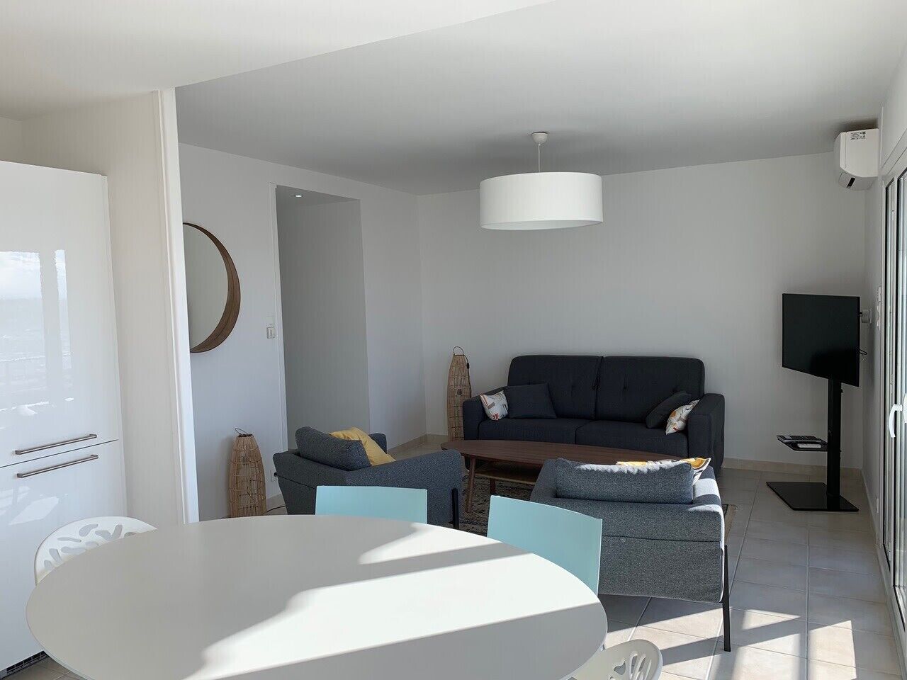 Ein modernes Wohnzimmer mit einer Couch, zwei Sesseln, einem Couchtisch und einem Fernseher.