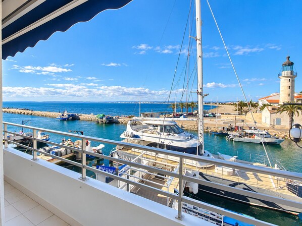 A marina with boats docked, a lighthouse, and a clear blue sky.