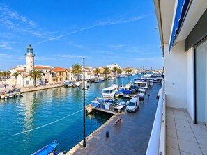 A marina with boats docked, a lighthouse, and buildings along the waterfront.
