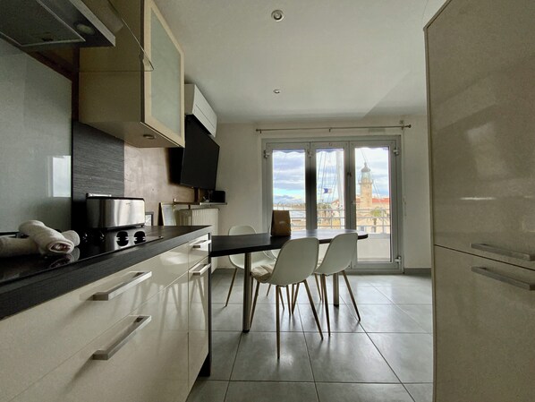 Een moderne keuken met een eethoek, met een groot raam en uitzicht op een vuurtoren en de zee.