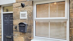 A stone building with a black door, a mailbox, and a window with blinds.