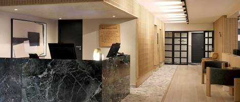 Un espace d’accueil doté d’un comptoir en marbre, de lambris en bois et d’un panneau présentant l’histoire de l’hôtel.