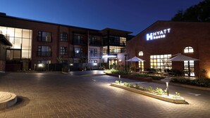 A Hyatt hotel with a brick facade, outdoor seating area, and a well-lit entrance. - Hyatt House Johannesburg, Sandton (Sandton)