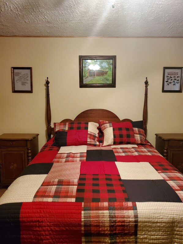 A bedroom with a large bed, two nightstands, a wooden headboard, and two framed pictures on the wall. - Snyder's Knob Bed and Breakfast (Newport)