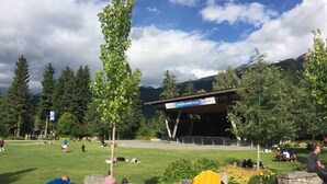 Een park met Adirondack stoelen, een podium en een bordje voor Whistler Olympic Plaza.