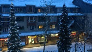 Een meerlaags gebouw met een met sneeuw bedekte nok, een zichtbare winkelvoorgevel met een 'Money Mart' bord en een 'Whistle Bungee' bord.