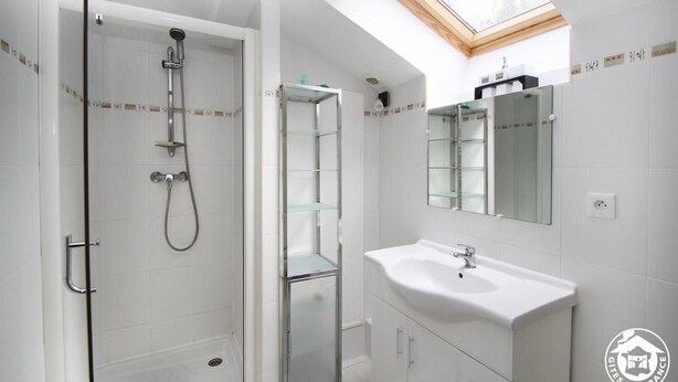 A modern bathroom with a glass shower enclosure, a white sink, and a skylight above the vanity. - A L'orée du Bois - Gîte (Hostun)