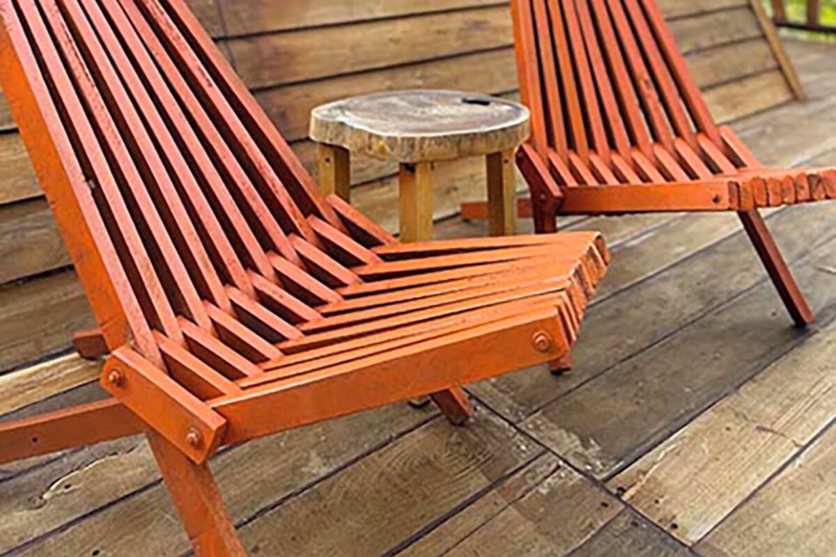 A wooden deck with two lounge chairs and a small table.