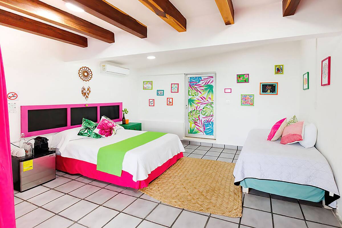 Une chambre à coucher avec un lit, des tables de chevet, une commode, une fenêtre et une porte.