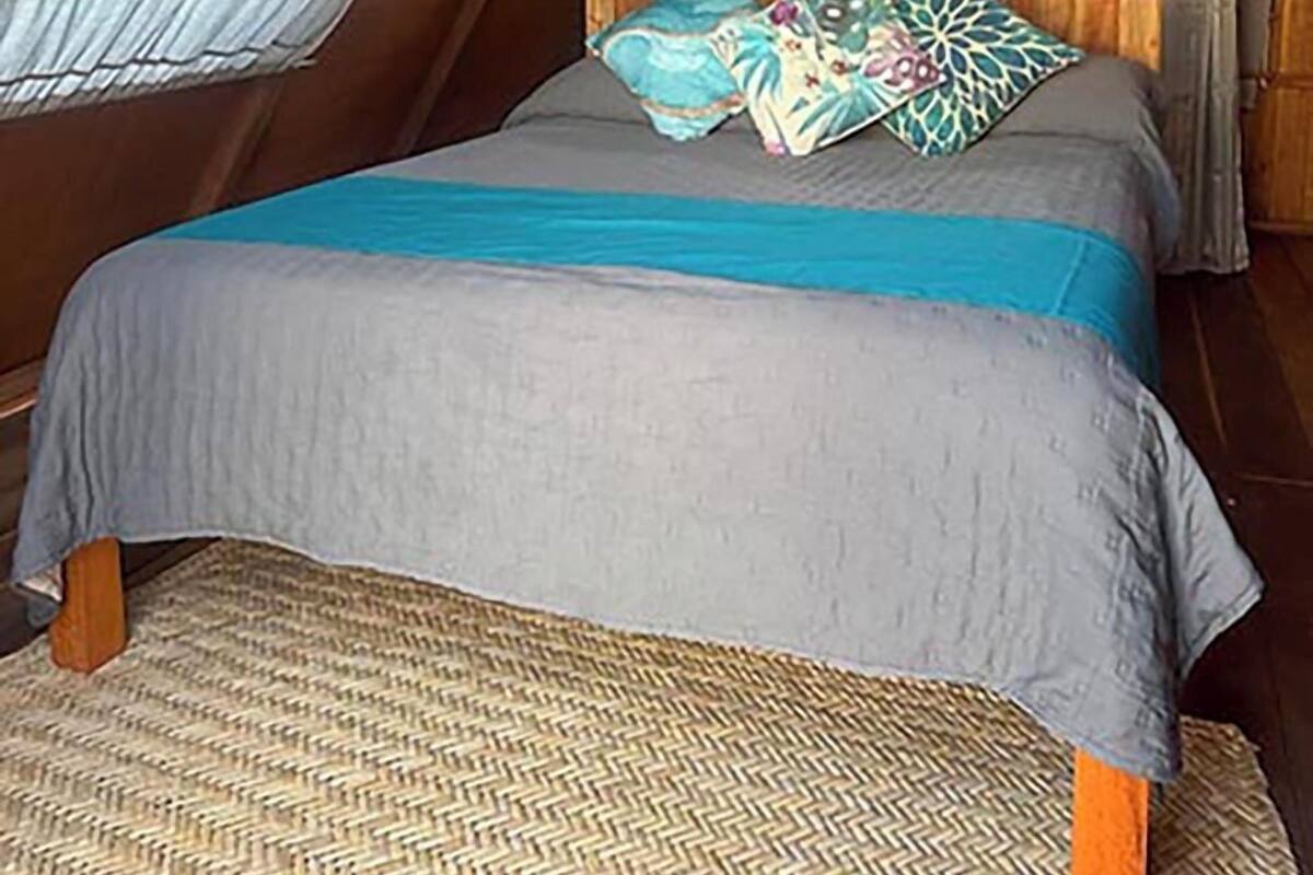 Une chambre à coucher triangulaire, chaleureuse et accueillante, avec un lit, des oreillers et une fenêtre.