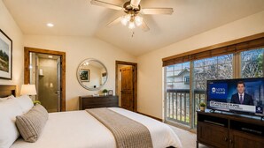 A bedroom with a bed, a ceiling fan, a TV, and a large window. - Trade the Office for Mountains at Foxpoint Townhouse 6180 (Park City)