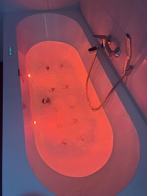 A bathtub with a shower head and a handheld shower attachment.