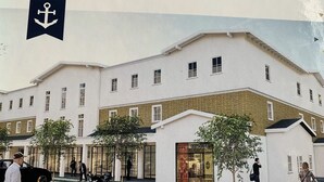 Un edifici de diversos pisos amb façana blanca i una secció inferior de maó, amb una botiga que diu "WAREHOUSE".