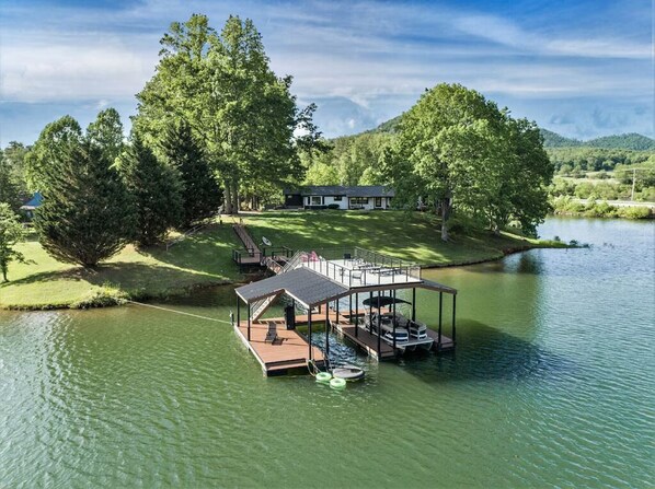 A lakeside property with a dock, a covered seating area, and a house in the background. - 1BR + Loft Lake Chatuge Cabin w/ Mountain Views (Hiawassee)