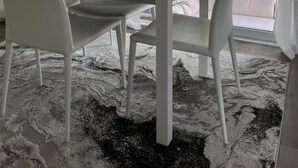 Un comedor moderno con una mesa de vidrio, sillas blancas y vista a una piscina.