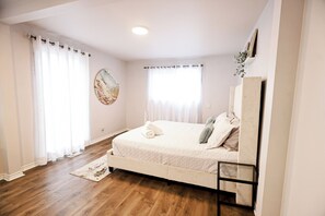A bedroom with a bed, a bedside table, a window with curtains, and a wall-mounted shelf. - Suburban Oasis with Private Pool, Jacuzzi & Gym! (Brantford)