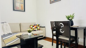 A modern living room with a sofa, a coffee table, a dining table with chairs, and two framed artworks on the wall. - BluO Modern Studio - Defence Colony Market (Delhi)