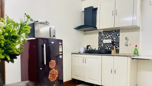A compact kitchen with a refrigerator, a stove, and white cabinets. - BluO Modern Studio - Defence Colony Market (Delhi)